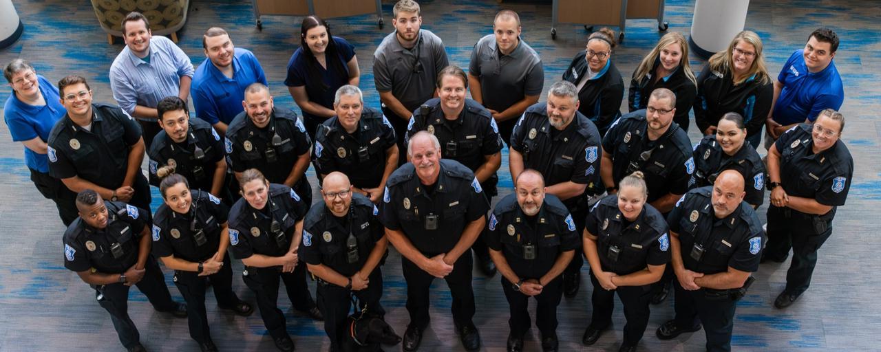 Group of police officers and civilian staff looking up at photographer